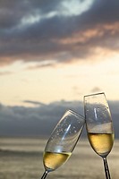 Two champagne flutes toasting against ocean background