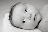 2 month old baby girl laying on a towel in the studio looking off camera.