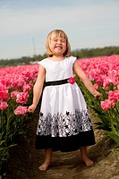 4 year old girl in black and white dress playing and smiling in a tulip fields in Skagit Valley, Washington, USA