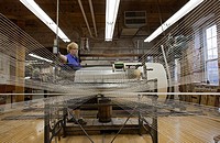 Amana, Iowa - A worker runs a warping creel at the Amana Woolen Mill  The machine gathers up to 240 strands of yarn that will later be woven into clot...