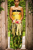 A Balinese woman holding a floral arrangement dress in a traditional Balinese dress