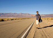 A man hitchhiking on rural desert highway