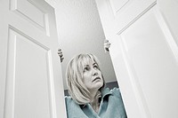 Middle-age blond woman looking out through double doors