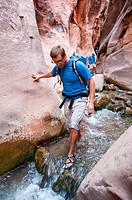 USA Utah, hike up the slot canyon known as Kanarra Creek, near Zion National Park, showing the red iron oxide rocks and the water stream erosion creat...