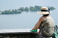 Woman sitting on a wall and watching islands on the water