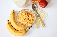 Breakfast cornflakes with milk and fruit  Cornflakes with bananas for healthy breakfast  Juice in lead glass  Nectarine  Yellow napkin with yellow fla...