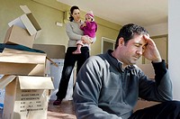 Young parents and their daughter stand beside cardboard boxes outside their home  Concept photo illustrating divorce, homelessness, eviction, unemploy...