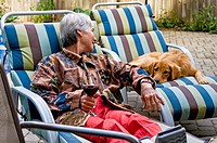 A woman relaxes with a dog on the deck in her backyard, Ontario, Canada