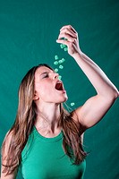 Young woman in green dropping green candy pieces in her mouth