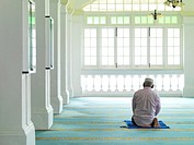 An elder man praying in a mosque