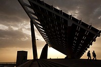 Two people walking under a giant solar panel in Barcelona