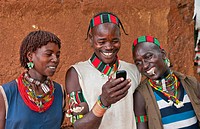 Dimeka Ethiopia Africa village Lower Omo Valley portrait of young Hamar guys and girl texting with cell phone communicating 18