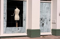 Fashion mannequin seen through whitewashed windows of an out of business closed shop.