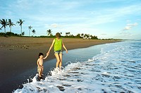 A mother taking her young son by the hand on the beaches of Bali