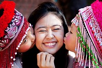 Two cute Meo Thai girls kissing an Asian tourist in Doi Suthep temple in Thailand
