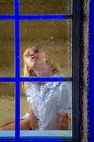A five-year-old girl looks out her window on a rainy night in suburban Lake Forest, CA