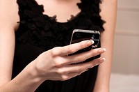 Pretty girl in little black dress texting on mobile phone