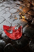 broken spiderman plastic mask on wet road in city town