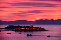 Red sky sunset at Kusadasi Turkey Harbour with lit Guvercin Adasi Island Genoese castle on the Aegean Sea with mountains of Samos Greece