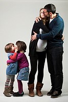 Family of four members in a photo studio kissing to each other.