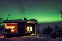 Cottage with northern light, aurora borealis in background in winter time at Riksgränsen in swedish lapland.