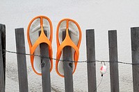 Flip Flops and fishing lure hanging on a beach dune fence. Lavalette, New Jersey, USA.