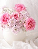 Pink and white flowers in a vase with white decorative fabric.