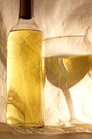 Dimly, a bright wine bottle and filled glass forms on and in tissue paper.  