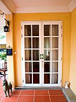 Double patio white french doors with windows on yellow wall.