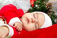 View of a newborn baby on a Christmas suit sleeping.