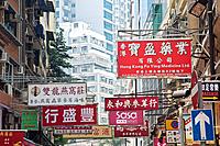 One of the countless busy streets in Hong Kong showing the signs that hang over head.