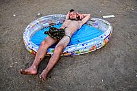 A naked man sleeping in a pump up pool at the Przystanek Woodstock Music festival in Kostrzyn, Poland.