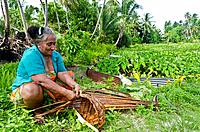 Local woman weaving basket from coconut palm frond, Nassau atoll, Northern Cook Islands, South Pacific.