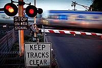 Passenger train moving rapidly through railway crossing with warning lights flashing, Melbourne Australia