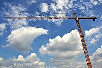 light blue sky with clouds with building crane running horizontally through the image.