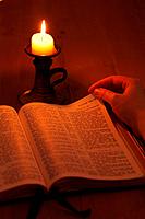 Bible and candle in dark.