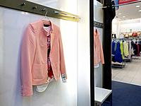 Woman`s jacket hanging in dressing cabin, reflection, mirror. Retail store, shop, shopping.