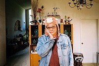 An older Asian man wears a monkey hat while holding his hand on his cheeks in the living room of his Californian home.