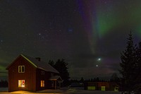 Northern light, aurora borealis in Gällivare, Swedish lapland with a house and light shining through the window and snow outside in the month of march...