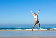 pregnant woman jumping on the beach.