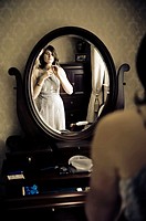 Young woman dressing in front of a vanity mirror.