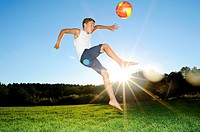 Young boy playing soccer on a meadow, Germany.