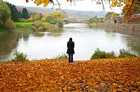 Autumn scene. Pensive woman at the river in Hannover Münden Germany.