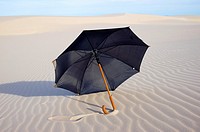 black rain umbrella on sand dunes, NSW coast, Australia.