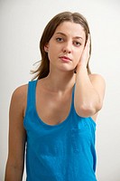 Young beautiful woman in a blue top, stopping both ears with her hand