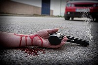 Man with gun in hand bloodstained lies dead in the asphalt murder victim.