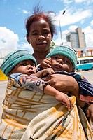A poor beggar carrying her baby twins in the streets of Antananarivo.