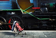 A baby carriage close to a old train in the station of the train museum of Madrid, Spain.