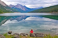 Woman sitting on rock and overlooking Medicine lake, near Jasper, Alberta, Canada.