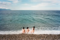 Three young woman in bathing suits enjoy the summer beach waves at Chi Shing Tan beach in Hualien, Taiwan